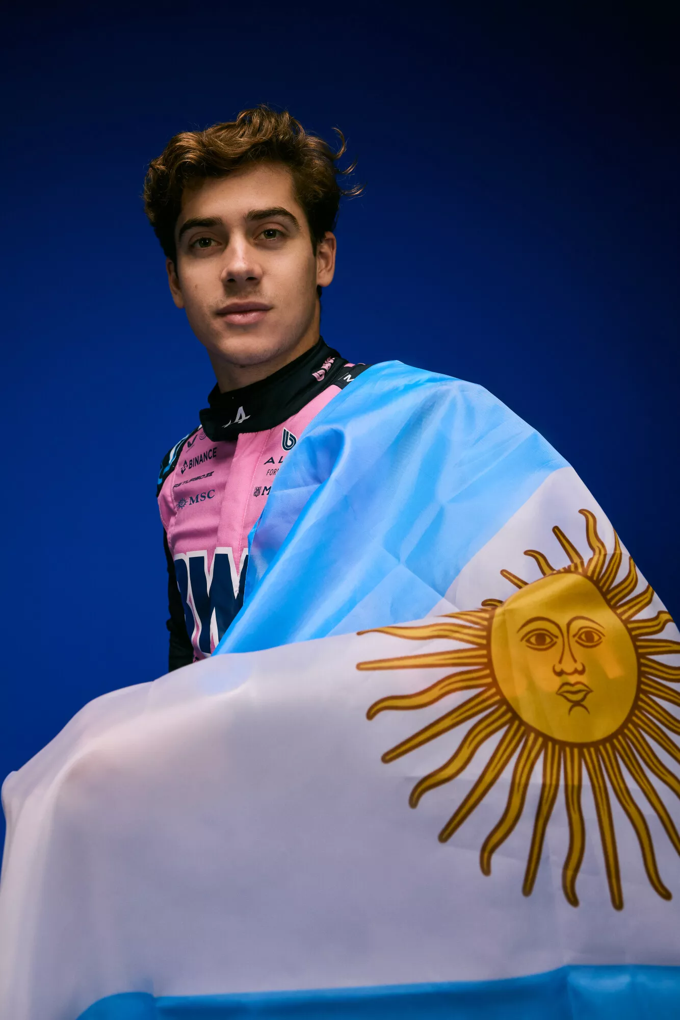 Franco con el traje rosa de Alpine y la bandera argentina sobre el hombro.