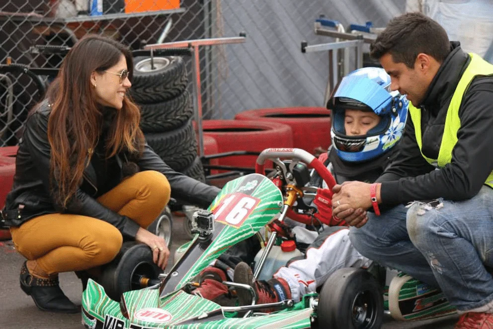 Franco de chico sentado en su kart, acompañado por su mamá y su papá.