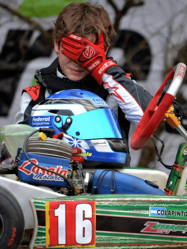 Franco de chico junto a su kart número 16, con el casco apoyado delante.